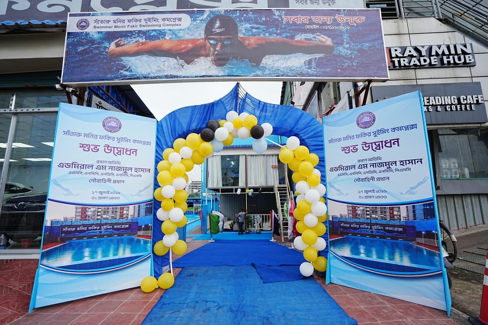 The inauguration archway at Monir Fokir Swimming Complex, a blue balloon tunnel over a red-and-blue carpet beneath a banner of a swimmer in mid-stroke.