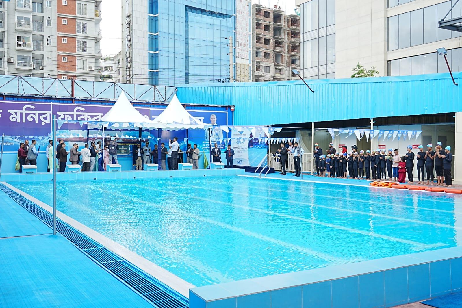 Guests and young swimmers applaud from the pool deck as the inauguration plaque is presented under the twin canopy tents.