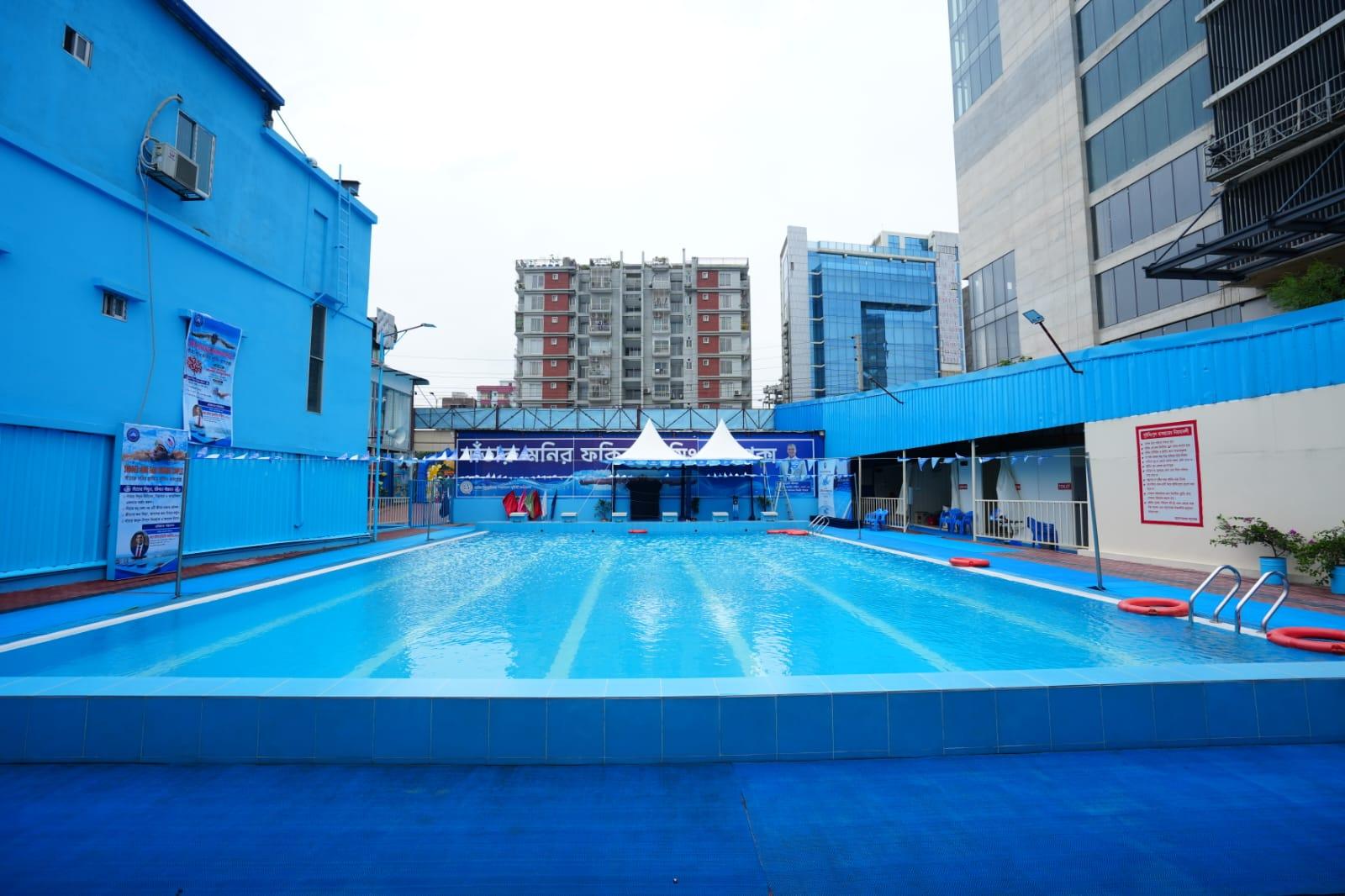 The pool deck framed between two of the complex's blue-clad buildings, with high-rises crowding the skyline beyond.